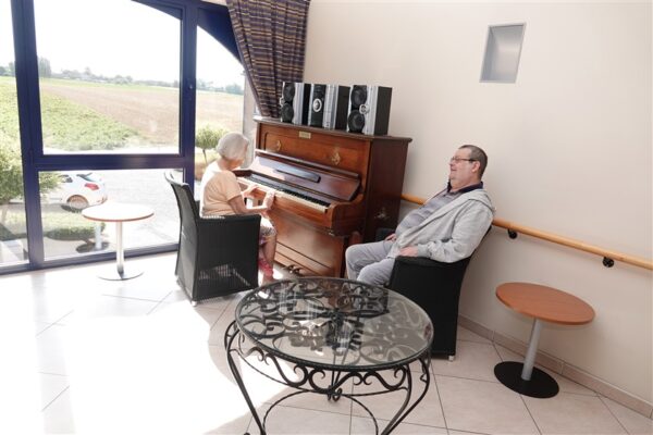 Ry du Chevreuil Piano avec une dame âgée qui joue et un homme qui écoute - Maison de repos - Eghezée